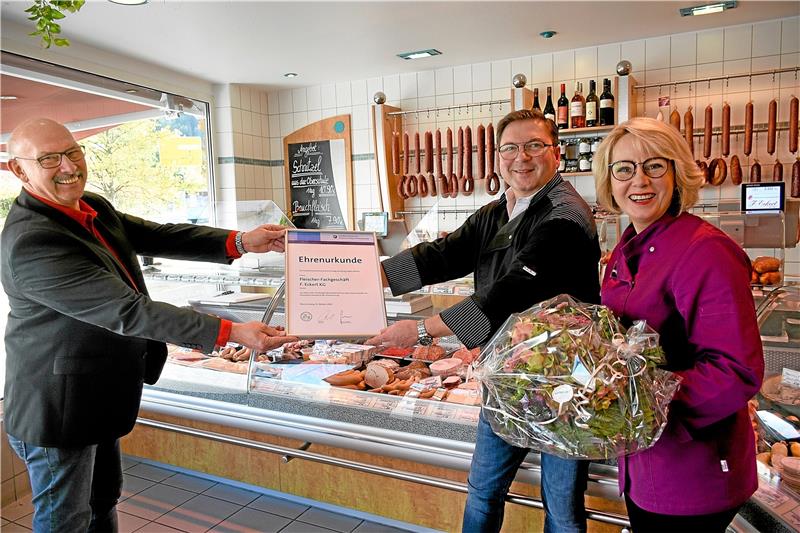 Kreishandwerksmeister Bernhard Olbrich (links) überreicht Stephan und Mona Henneberg eine Ehrenurkunde für das 75-jährige Betriebsjubiläum. Mona Henneberg, geborene Eckert, ist die 1. Verkäuferin im Laden an der Bahnhofstraße 1.  Foto: Kempfer