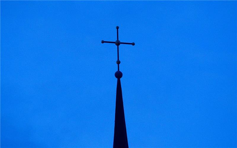 Kritik an Umgang mit Missbrauch in evangelischer Kirche Kreuz einer evangelisch-lutherischen Kirche in der Abenddämmerung.