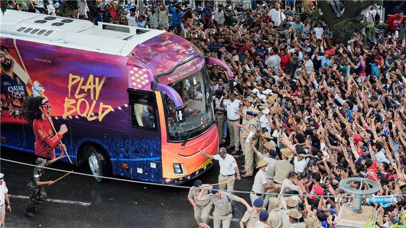 Kricket-Fans in Bengaluru jubeln ihrem Heimteam zu, das in einem Bus sitzt.