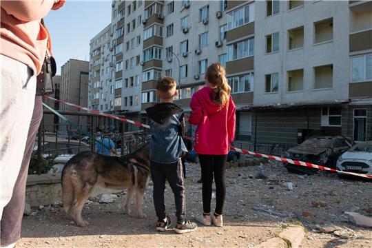Kriegsalltag: Kinder schauen in Kiew auf ein bei russischen Raketenangriffen beschädigtes Gebäude.
