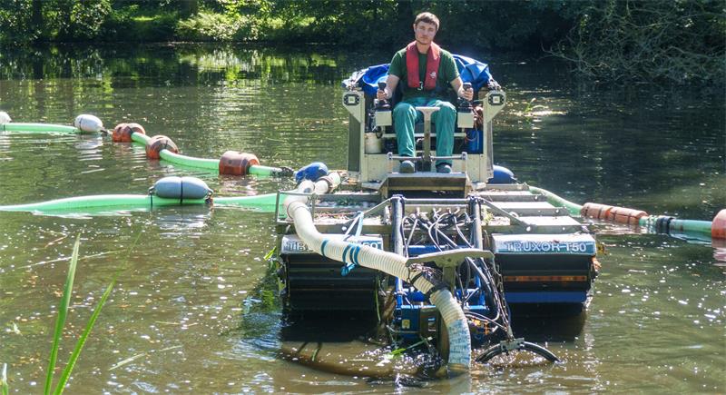 Kristian Rolle saugt von seinem Amphibienfahrzeug aus Sedimente vom Gewässergrund.