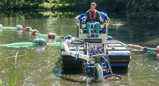 Kristian Rolle saugt von seinem Amphibienfahrzeug aus Sedimente vom Gewässergrund.
