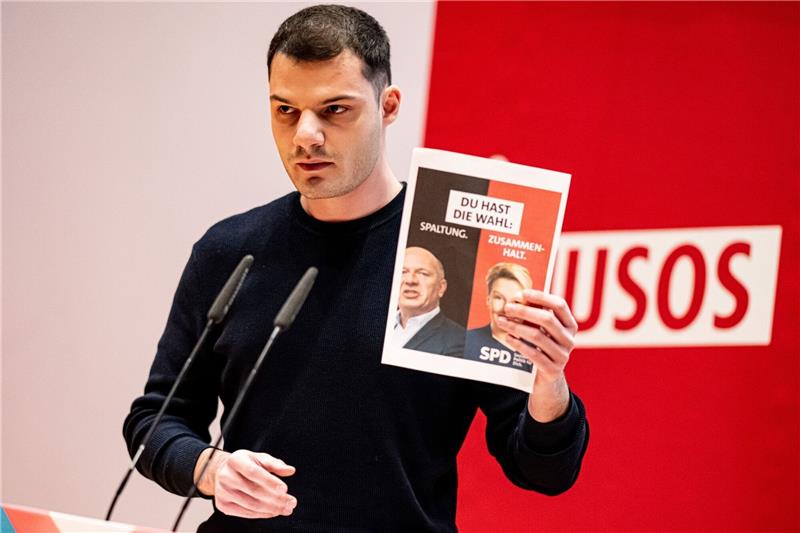Kubilay Yalcin, Delegierter, hält auf der Landesdelegiertenkonferenz der Jusos Berlin ein Wahlplakat mit Giffey und Wegner in die Höhe.