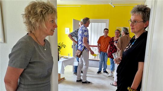 Künstlerin Dr. Paula Memel (r.) kommt auf dem Kunsthandwerkerhof mit Besuchern ihrer Ausstellung ins Gespräch – so auch mit Kurdirektorin Bettina Beimel (l.).