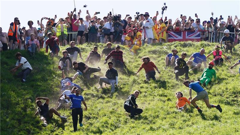 Kurioser Kultlauf in Gloucestershire: Beim Käserennen 2026 rennen Männer dem rollenden Käselaib den Hügel hinunter nach.