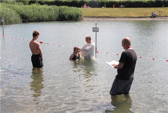 Kurz vor dem Schwimmerbereich des beliebten Badeteichs in Schladen tauft Pfarrer Olaf Schäper ein junges Mädchen. Foto: Hohaus