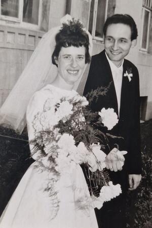 65 Jahre Ehe: „Ich wollte nie einen Kirchenmusiker heiraten“ Braut und Bräutigam in Hochzeitskleidung halten sich an den Händen, die Braut trägt einen Schleier und hält einen großen Blumenstrauß.