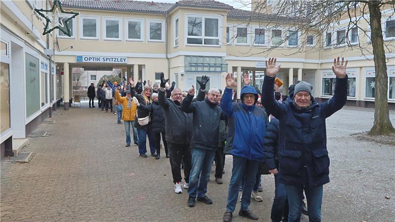Der GZ-Schweinchenverkauf läuft in Goslar auf Hochtouren Mehrere Personen stehen in einer Reihe auf einem gepflasterten Platz vund heben die Arme nach oben