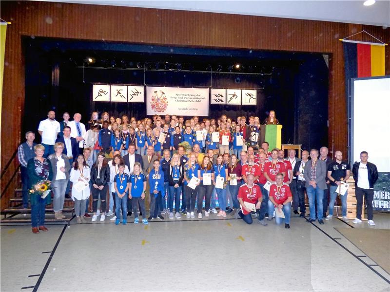 Medaillenregen in der Stadthalle Landessieger, Bezirks- und Kreismeister, Medaillengewinner bei Deutschen, Europa- und Weltmeisterschaften sind auf der Stadthallenbühne zur Sportlerehrung 2019 versammelt, eingerahmt von Trainern und Organisatoren, Sponsoren und Repräsentanten der Stadt. Vorn in Rot die TuS-Fußballsenioren, Mannschaft des Jahres. Fotos: Ebeling/Neuendorf.