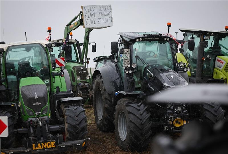 Landwirte stehen mit ihren Traktoren vor einem Zentrallager von Aldi.