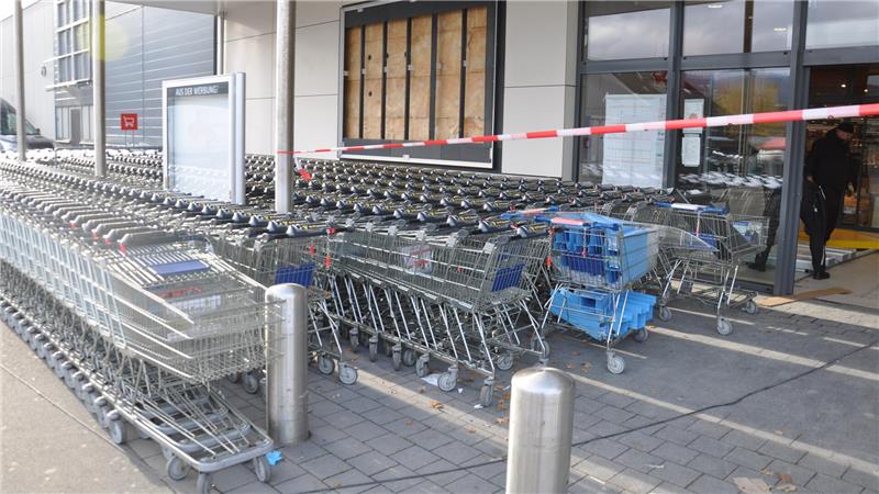 Reihen von Einkaufswagen mit blauen Griffen stehen vor dem Edeka-Gebäude.
