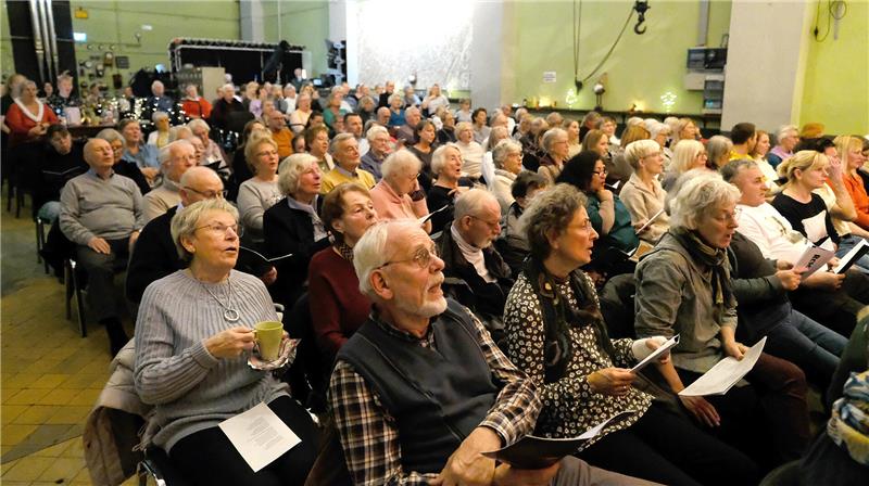 Gemeinsames Singen stimmt aufs Weihnachtsfest ein Viele Menschen sitzen in einem Raum und singen.