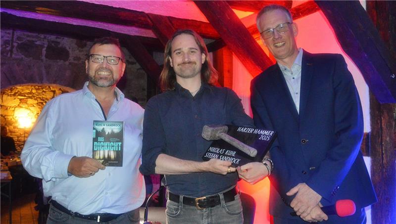 Literaturpreis geht an Autorenduo Nikolas Kuhl und Stefan Sandrock Laudator Andreas Gruber (links) und Festivalleiter Christoph Lampert (rechts) umrahmen den Preisträger: Nikolas Kuhl nimmt beim Mordsharz-Auftakt in Wernigerode den „Harzer Hammer“ für seinen Krimi „Das Dickicht“ entgegen.