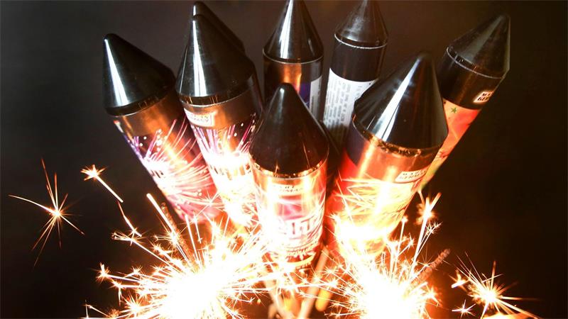 Mehrere Feuerwerksraketen mit schwarzen Spitzen, die von Funken umgeben sind.