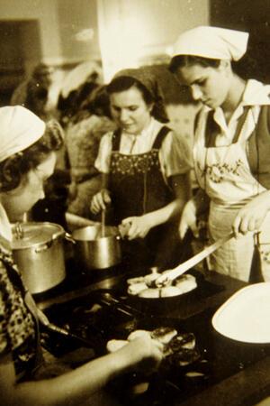 Rätselhaft: Was zeigen diese alten Bad Harzburger Schulfotos? Das historische Bild zeigt junge Frauen an einem alten Herd.