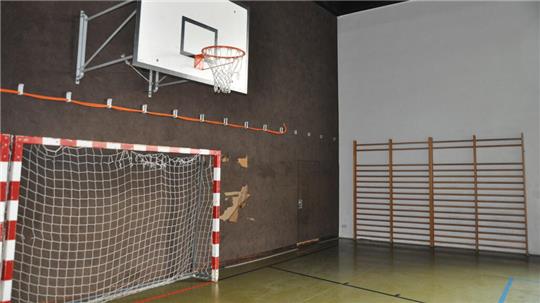 Innenaufnahme einer Sporthalle mit Basketballkorb, Handballtor und Sprossenwand an der Wand