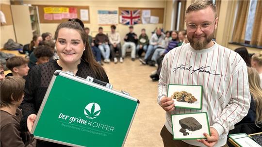 Leonie Krause und Philipp Piskol betreuen das Präventionsprojekt, in dessen Mittelpunkt ein grüner Koffer steht.