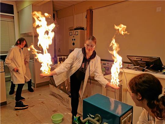 Leonie steht bei der Chemie-Show in Flammen – aber keine Angst: Auf ihren Händen und Füßen hat sie einen Schaum aus Spülmittel, Alkohol und Gas. An ihrem Körper merkt sie daher das Feuer nicht. Foto: Knoke