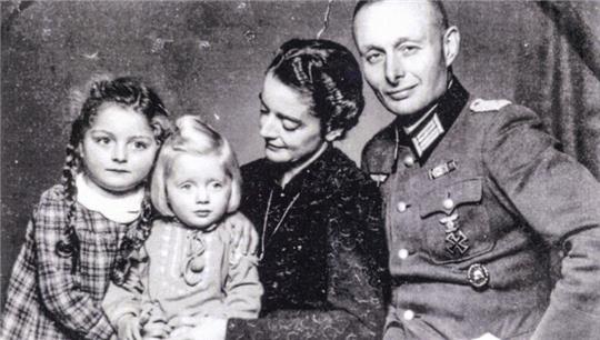 Schwarz-weiß-Familienporträt mit zwei Kindern, einer Frau und einem Mann in Uniform, die nebeneinandersitzen.