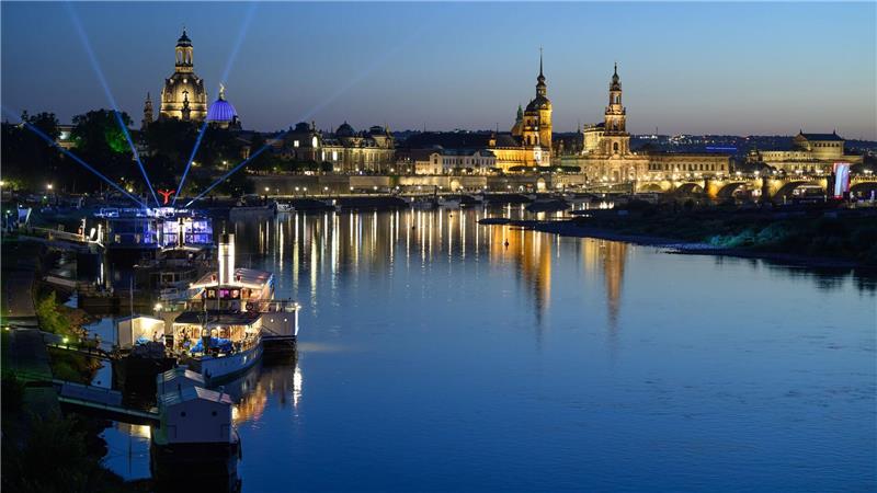 Lichter einer Party auf einem Schiff der Sächsischen Dampfschifffahrt Weiße Flotte sind am Abend vor der historischen Altstadtkulisse in Dresden an der Elbe mit der Frauenkirche (l-r), der Kuppel der Kunstakademie mit dem Engel „Fama“, dem Terrassenufer, dem Ständehaus, dem Hausmannsturm, der Hofkirche und der Semperoper zu sehen. 