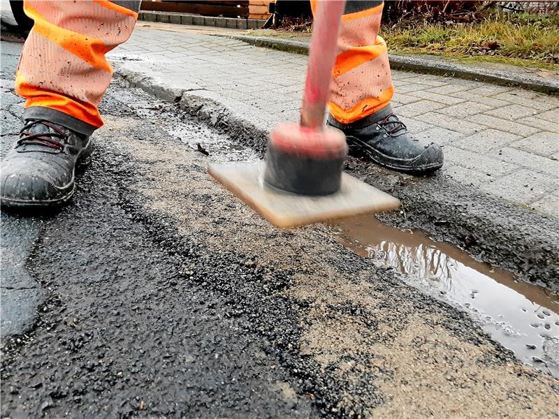 Löcher in den Straßen können während der Wintermonate nur mit Kaltasphalt verfüllt werden. Vorab wird das lose Material entfernt und die Stelle ausgefegt. Foto: Potthast