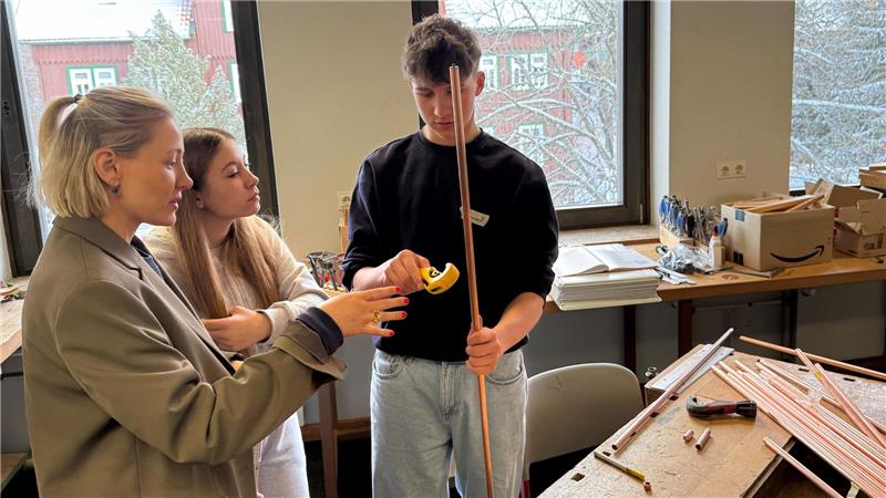 Das Foto zeigt eine Frau, die zwei Schlülern etwas erklärt.