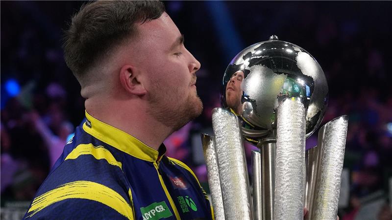 Luke Littler küsst die Trophäe nach seinem Sieg im Endspiel der Darts-WM.