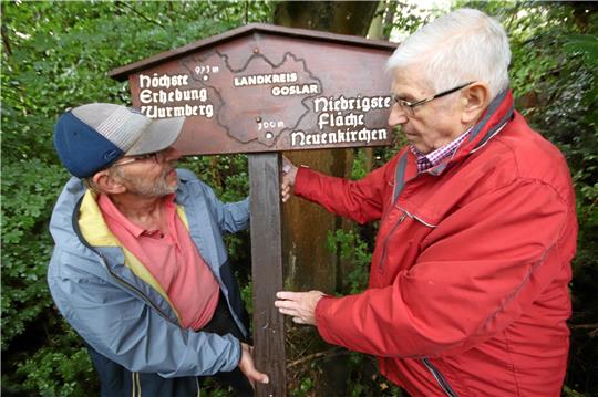 Lutz Griesbach und Klaus Stövesand (v.li.) vom Heimatkreis Neuenkirchen stellen bei Lüderode das restaurierte Schild auf, das auf die niedrigste Fläche hinweist. So manch ein Passant hatte es in den vergangenen Wochen vermisst. Foto: Gereke