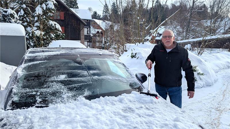 Lutz Meier fegt Schnee von seinem Auto