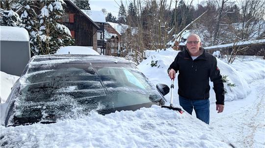 Lutz Meier fegt Schnee von seinem Auto