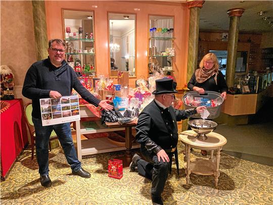 Lutz Mrozek, Schornsteinfeger Frank Dornemann und Annemarie Kinzel (von links) ziehen im Café Peters die Tombola-Lose.