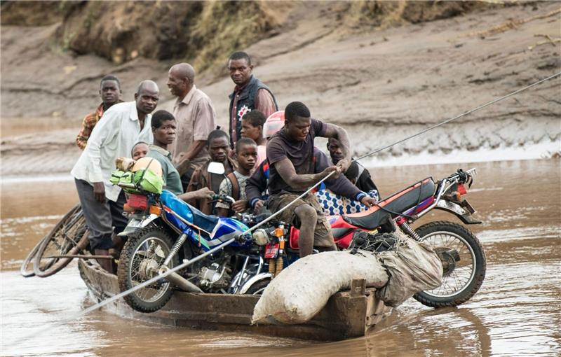 Opferzahl nach Tropensturm „Freddy” steigt auf 531 Männer transportieren in Malawi ihre geretteten Habseligkeiten mit einem Holzboot.