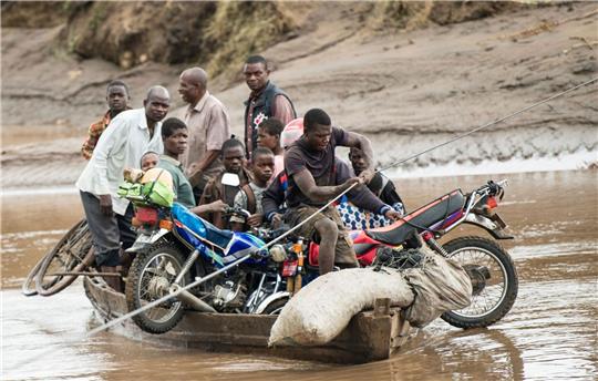 Männer transportieren in Malawi ihre geretteten Habseligkeiten mit einem Holzboot.