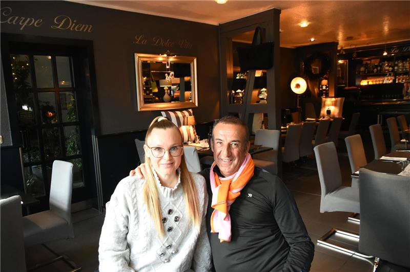 Ein Paar sitzt, vom Tageslicht angestrahlt, allein in einem schicken Restaurant.