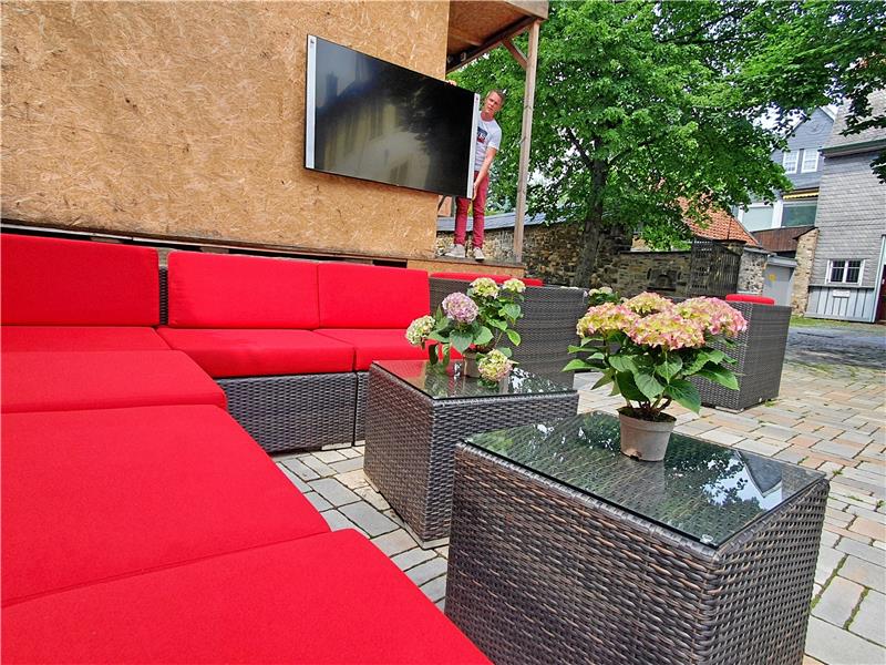 Maik Jankowsky, Gastronomieleiter im Hotel „Alte Münze“, positioniert schon einmal den Fernseher im Garten der Herberge.  Foto: Sowa