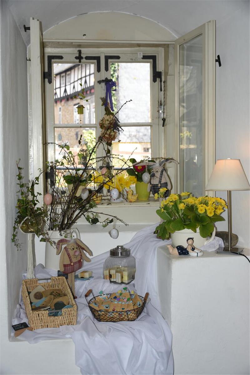 Frühlingshaft dekorierte Fensternische mit Zweigen, gelben Blumen und Osterkörben.
