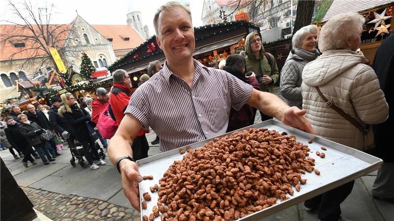 Wo im Landkreis Goslar und der Region Weihnachtsmärkte stattfinden Mandelbrenner Markus Meier hält ein Tablett mit frisch gebrannten Mandeln an seinem Verkaufsstand auf dem Weihnachtsmarkt in Braunschweig in den Händen.