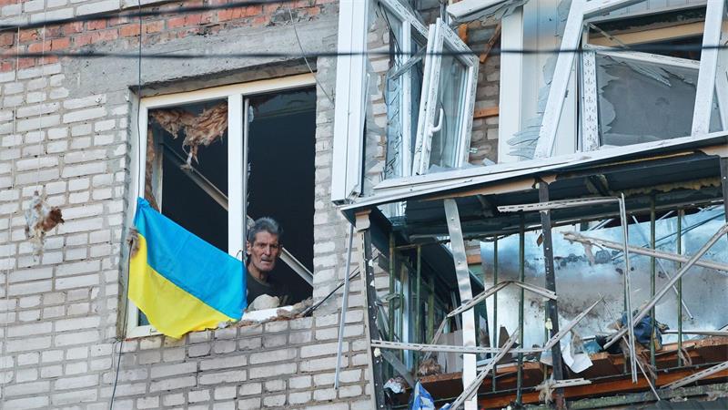 Mann blickt durch ein zerbrochenes Fenster in Saporischschja nach russischem Angriff