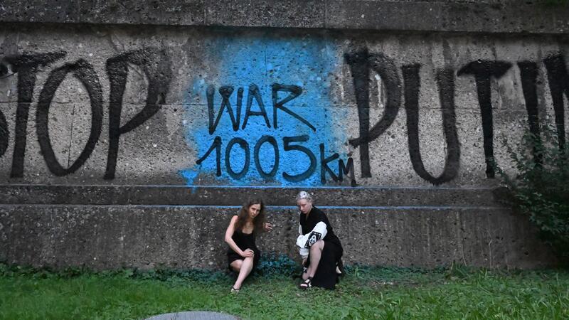 Marija Wladimirowna Aljochina und Taso Pletner von Pussy Riot sitzen bei der Eröffnung der Ausstellung „Velvet Terrorism: Pussy Riot’s Russia“ vor einem Graffiti in München.