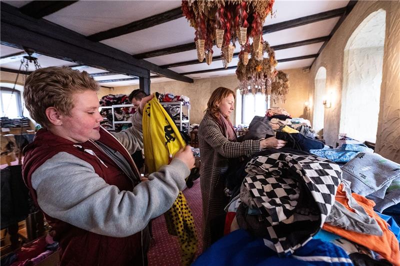 Mark und Mutter Julia aus der Ukraine stehen an gespendeten Kleidungstücken in der ehemaligen «Keiler Schenke».