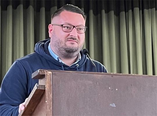 Ein Mann steht an einem Pult und spricht.