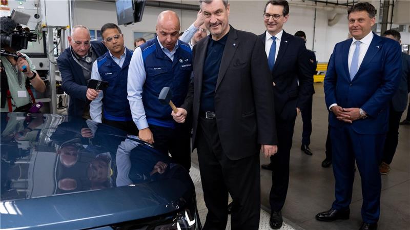 Markus Söder (CSU) bringt mit einem Hammer das BMW-Logo an einem Auto an.
