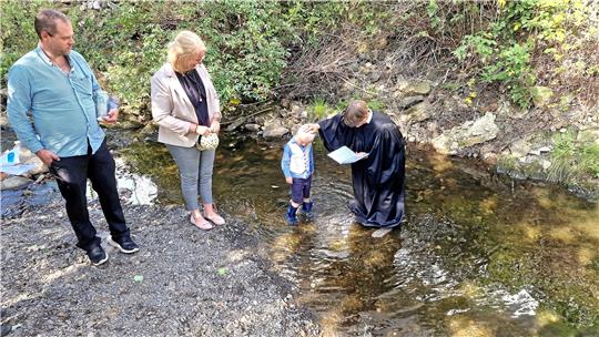 Maximilian Gerlach nimmt in der Oker unter den Augen der Eltern den Taufsegen von Pastorin Louisa Frederking entgegen. Foto: Weiss