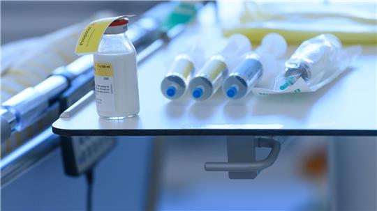 Medikamente liegen auf einem Tisch an einem Krankenbett.