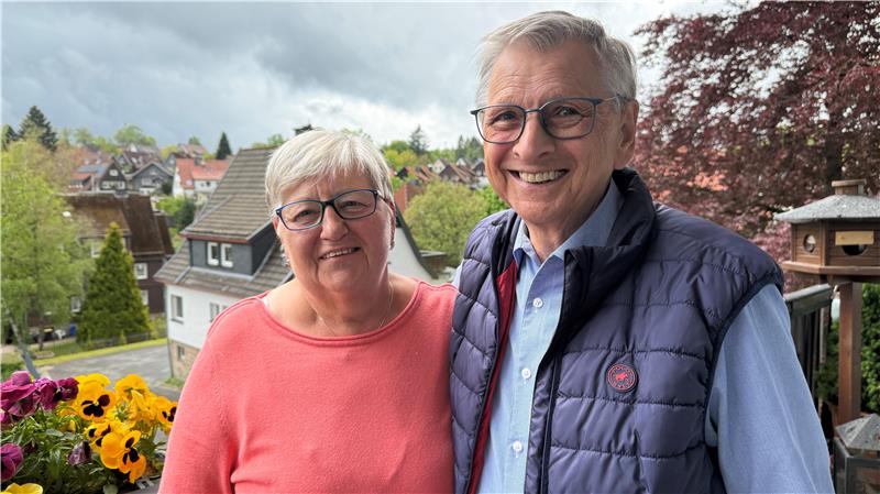 Das Foto zeigt ein Paar auf einem Balkon, das sich umarmt.