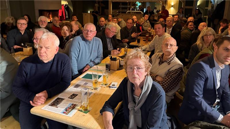 Das Foto zeigt viele Menschen, die an Tischen sitzen.