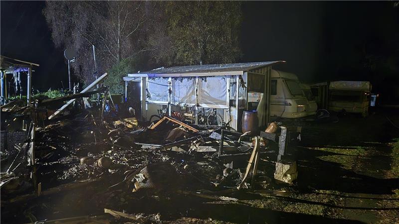 Eine abgebrannte Parzelle. Verkohlte Trümmer und Überreste eines Pavillons stehen noch herum.