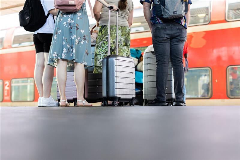 Mehrere Personen stehen mit Koffern auf einem Bahnsteig vor einem Regionalexpress im Hauptbahnhof Hannover.