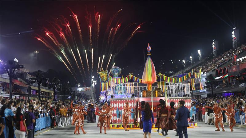 Mehrere Sambaschulen ziehen mit bunten Wagen durch die Straße.