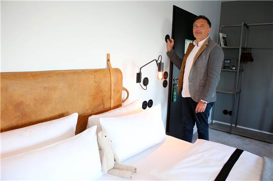 Meik Lindberg, Eigentümer des „The Hearts Hotel“, stellt über ein Regelsystem die Temperatur in einem Hotelzimmer ein. Das Hotel kann die Ober- und Untergrenze der Temperatur zentral steuern. Foto: Stefan Rampfel/dpa